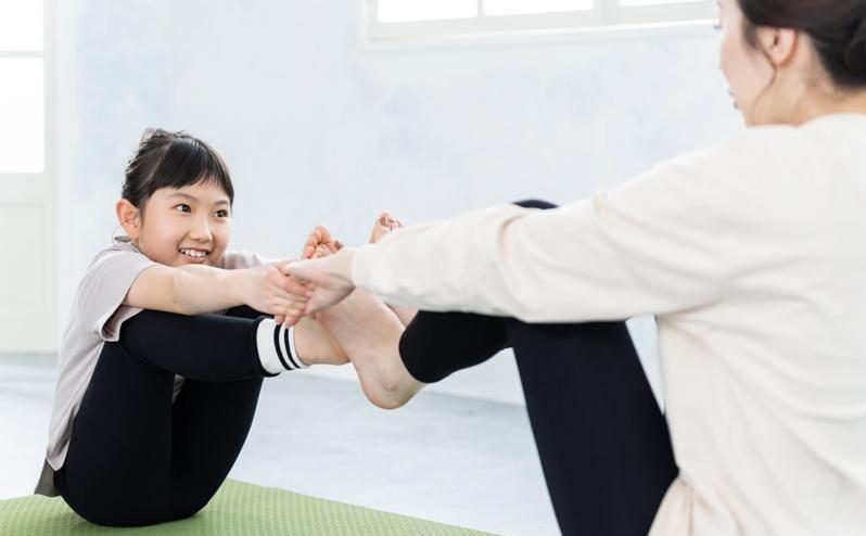 子どもとトレーナーがマットの上で体幹トレーニングをする様子