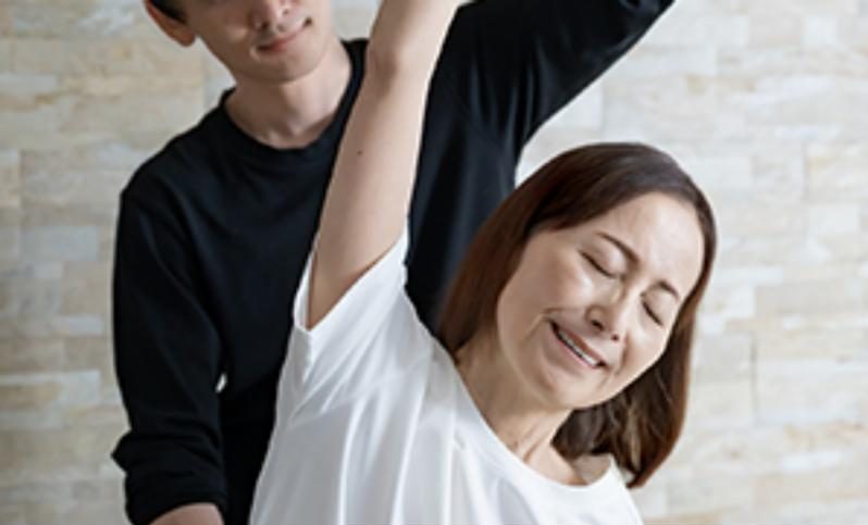 トレーナーが肩まわりの動きを確認している様子